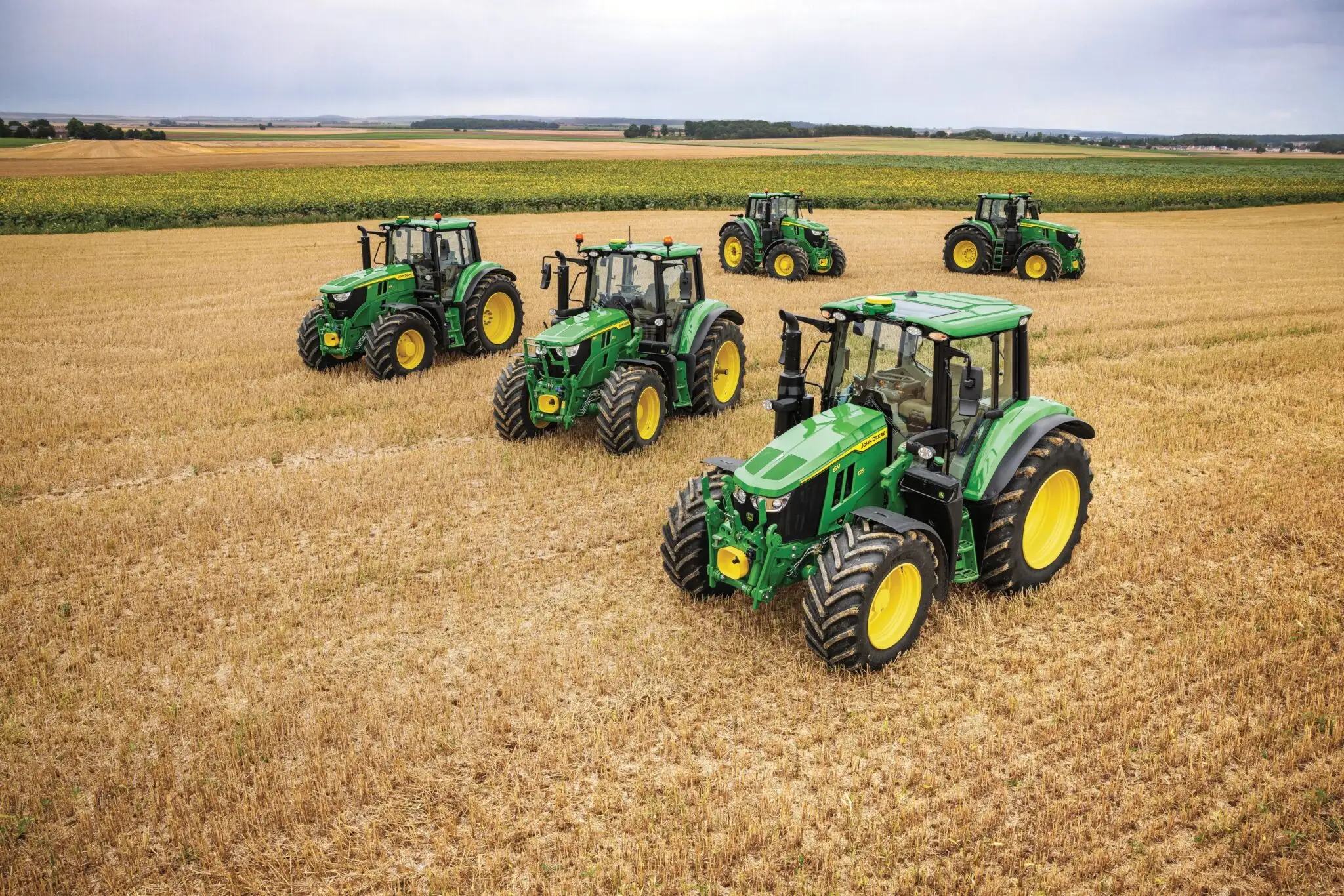 Fünf John Deere Traktoren, die auf einem Feld stehen