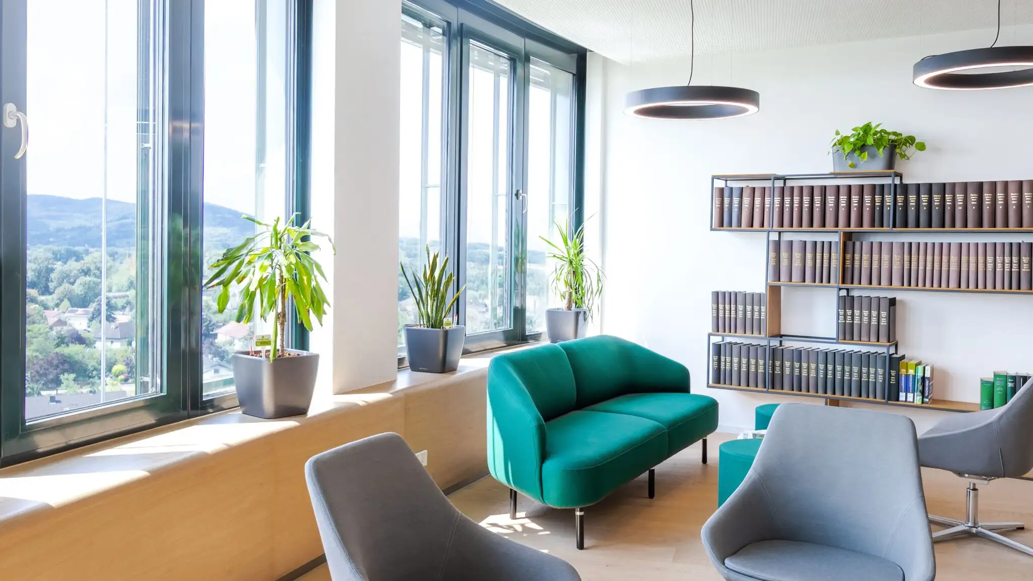 Aufenthaltsraum mit Sitzgruppe, Bücherregal und Fensterfront