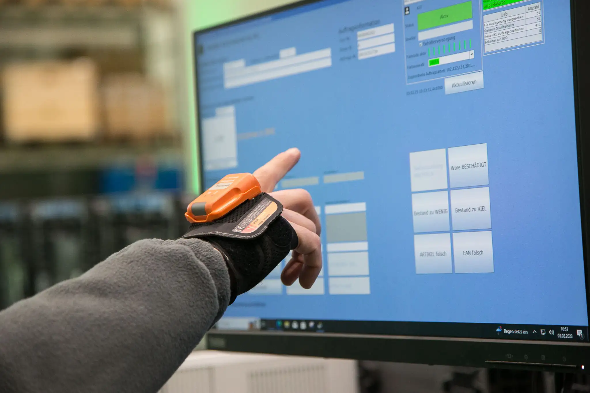 Hand mit Handscanner zeigt auf einenMonitor